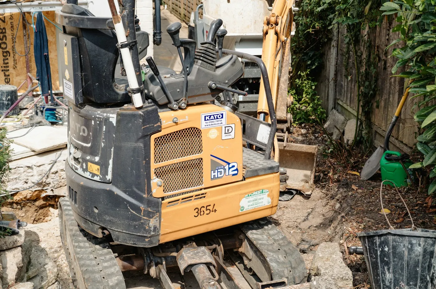 Compact excavator beside a residential structure