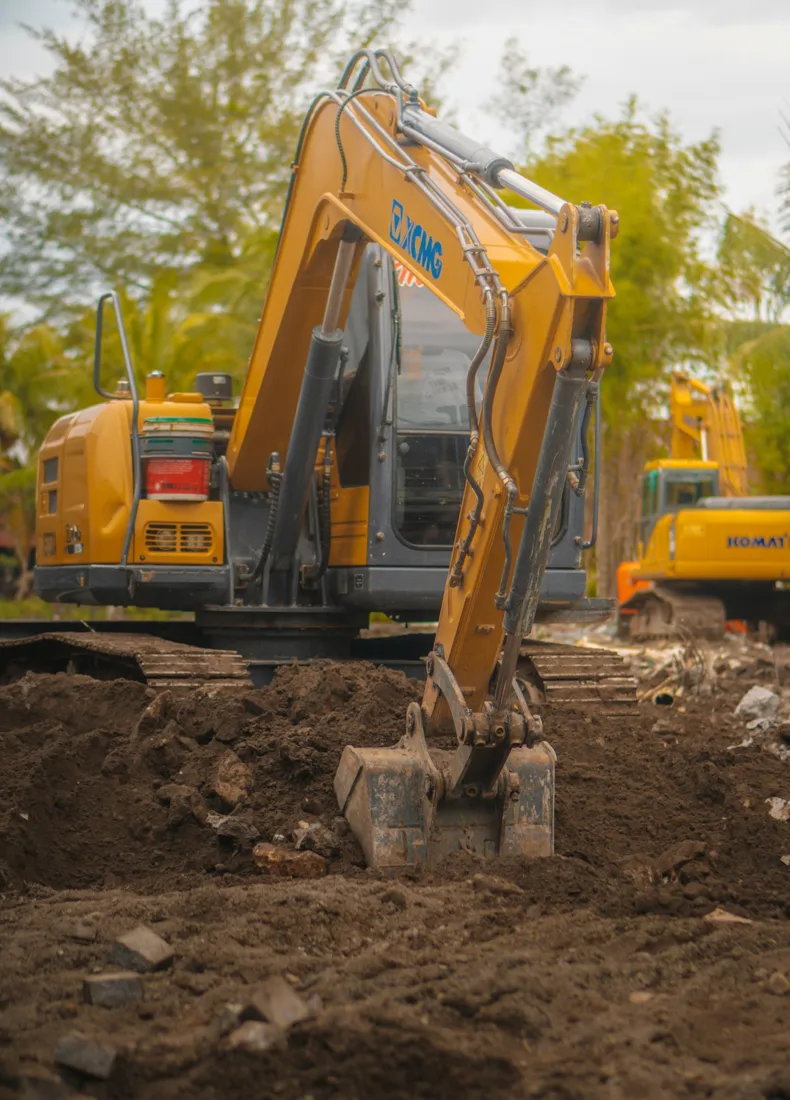 Excavator digging soil in a treed work area
