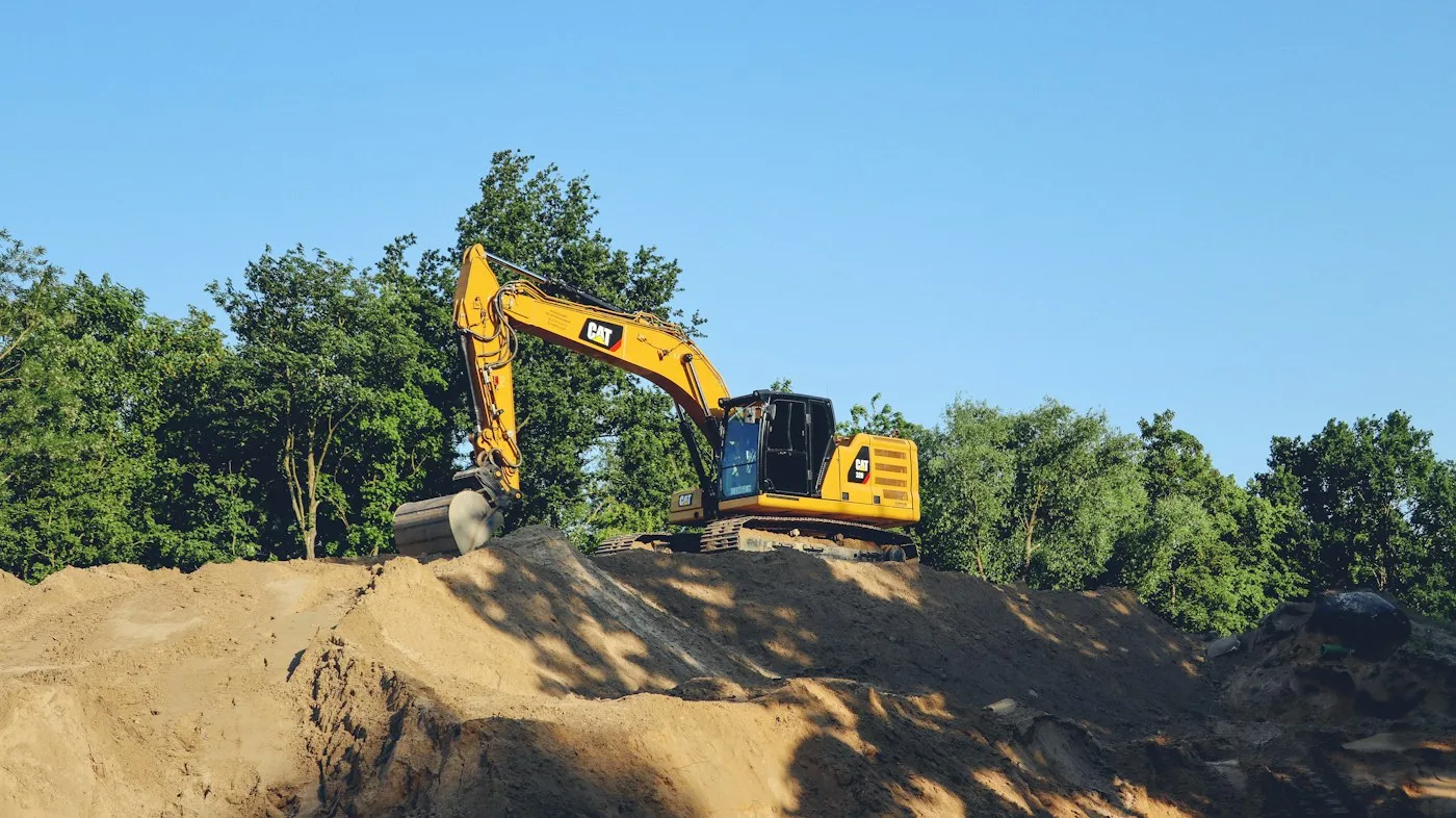 Excavator working among soil stockpiles